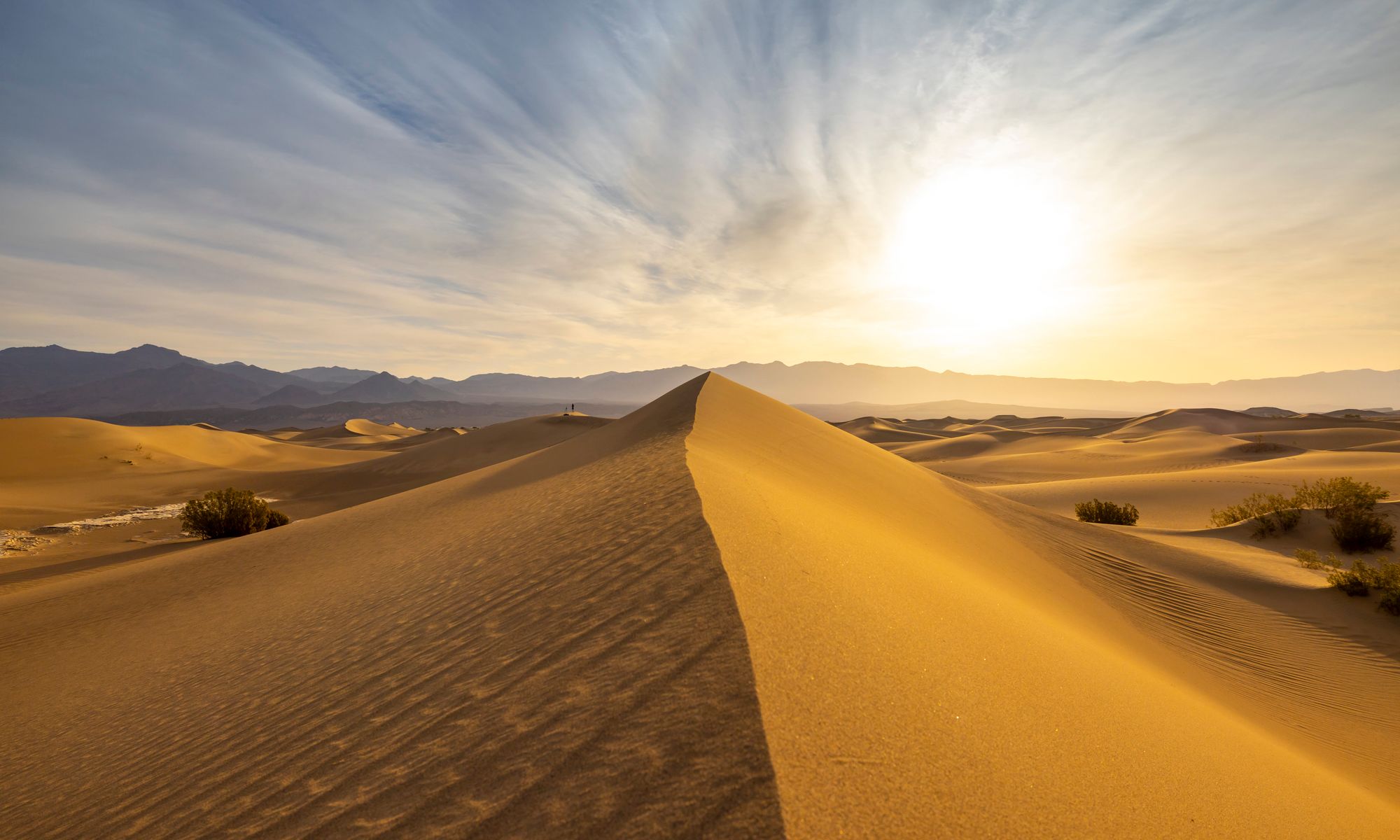 Golden sand dunes under a bright sun in Death Valley